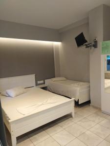 a bedroom with two beds and a tv on the wall at Miltos rooms in Leptokarya