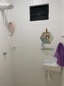 La salle de bains blanche est pourvue d'un lavabo et d'une douche. dans l'établissement Casa Ampla perto de uma das melhores praia de SSA, à Salvador