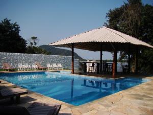 a swimming pool with a gazebo and a table at Pousada Recanto das Aves in Iguape
