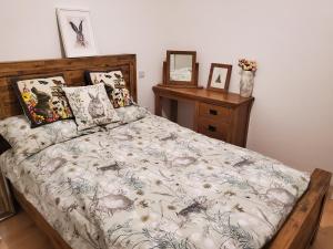 a bed with a comforter and pillows in a bedroom at Cosy cottage in the Blackdown Hills Devon in Honiton