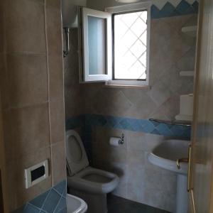 bagno con servizi igienici, lavandino e finestra di Il Sestante di Manuela a Cala Liberotto