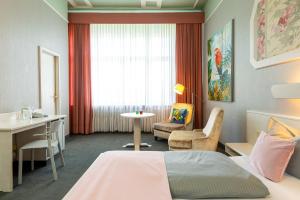 ein Hotelzimmer mit einem Bett, einem Schreibtisch und einem Tisch in der Unterkunft W22 Hotel am Kurfürstendamm in Berlin