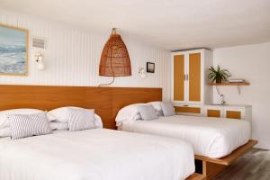 two beds in a room with white sheets at Bluebird Parker Beach Lodge in South Yarmouth