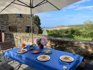 a blue table with plates of food and an umbrella at Cancale Chapelle du Verger in Cancale