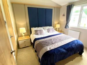 a bedroom with a large bed with a blue headboard at Meadow Lodge in Scarborough