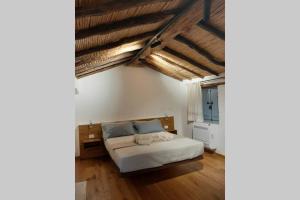 a bedroom with a bed and wooden floors and exposed ceilings at Casetta da scoprire a due passi dal centro in Tortolì