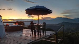 Arbeláez的住宿－Glamping Altos De Tiscince，甲板上的桌椅和遮阳伞