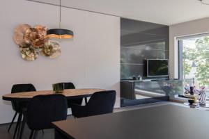 a dining room with a table and chairs and a television at Boulevard Botanie city apartment with parking in Hasselt