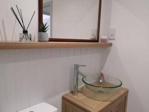 a bathroom sink with a glass bowl on a wooden stand at The Little House, boutique home near the sea in Chichester