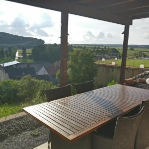 a wooden table and chairs on a porch with a view at Ferienwohnung Erlenbach-Marktheidenfeld in Erlenbach bei Marktheidenfeld