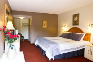 - une chambre avec un lit et un vase de fleurs dans l'établissement Niagara Falls Motor Lodge, à Niagara Falls