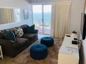 sala de estar con sofá y 2 reposapiés azules en Sands Beach Breaks Umdloti Beach View, en Umdloti