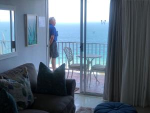 a man standing on a balcony looking out at the ocean at Sands Beach Breaks Umdloti Beach View in Umdloti