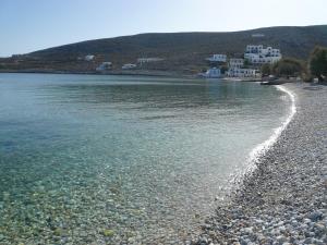 a beach with rocks and houses in the background at Vrahos Boutique Hotel in Karavostasi