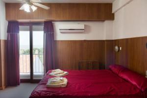 a bedroom with a red bed with towels on it at Hotel Stella Marina in San Clemente del Tuyú