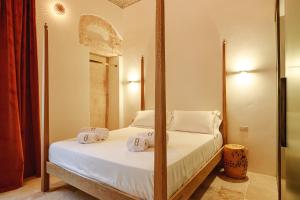 a bedroom with a four poster bed with white sheets at BAYIT Charming Place in Polignano a Mare