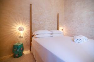 a bedroom with a bed with white sheets and a lamp at BAYIT Charming Place in Polignano a Mare