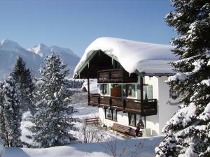 un edificio cubierto de nieve con árboles y montañas en Haus Schöneck - Chiemgau Karte, en Inzell