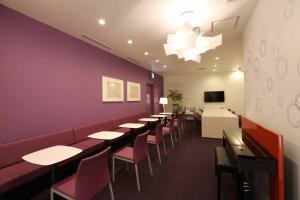 un restaurant avec des tables et des chaises et un mur violet dans l'établissement First Cabin Hakata, à Fukuoka