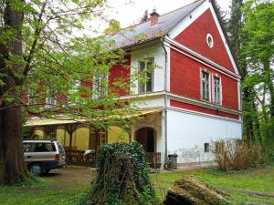 a red and white house with a car parked in front at Kalmár Vendégház-Vadászház in Tornyiszentmiklós