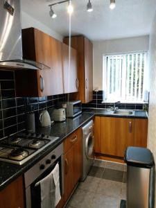 a kitchen with wooden cabinets and a stove top oven at Heronsgate GH008 in Thamesmead