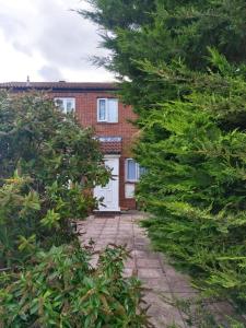 a brick house with a white door and trees at Heronsgate GH008 in Thamesmead