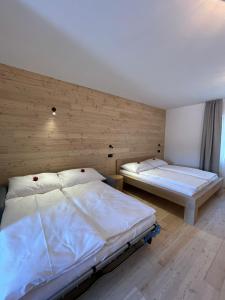 two beds in a room with wooden walls at Penzion Kolnička in Luka nad Jihlavou