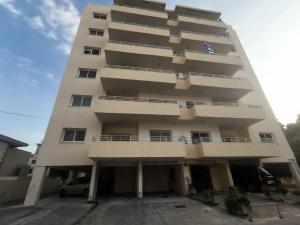 a tall white building with a parking lot at Sunny 2 Bedroom Larnaca Center in Larnaca