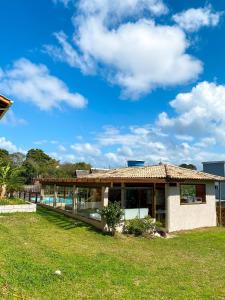 a house with a roof on a grass field at Rosamar Suites in Praia do Rosa