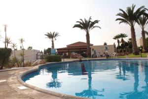 a large swimming pool in a resort with palm trees at Happy Holiday in Coral Bay +16 photos