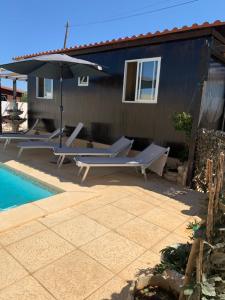 a patio with chairs and an umbrella next to a pool at Casinha do Rogel in Alcantarilha