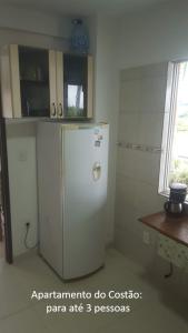 a kitchen with a white refrigerator in a room at De frente para o Mar da Gamboa in Garopaba