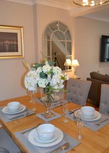 a dining room table with plates and a vase of flowers at Sea Haven in Conwy
