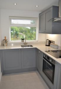a kitchen with gray cabinets and a sink and a window at Sea Haven in Conwy