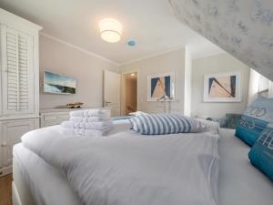 - une chambre blanche avec un grand lit blanc et des oreillers dans l'établissement Haus Nordlicht, à Zingst