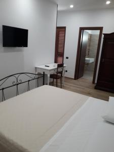 - une chambre avec un lit, une table et une télévision dans l'établissement Angelica, à Lecce