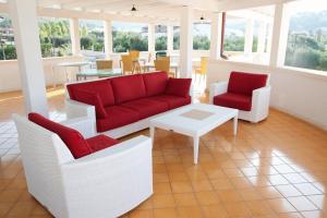 a living room with a red couch and two chairs at Ganimede Hotel in Sperlonga