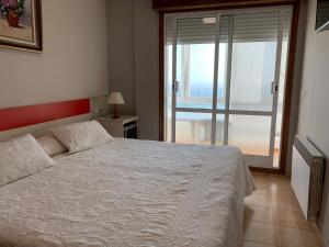 a bedroom with a white bed and a large window at Hotel Playa in Cangas de Morrazo