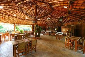 a restaurant with tables and chairs and a wooden ceiling at Pousada Recanto das Aves in Iguape