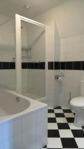 baño blanco con bañera y aseo en B&B Sagenland, en Harbrinkhoek