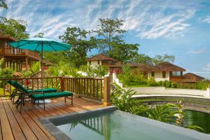a deck with an umbrella and a chair and a pool at La Coralina Island House in Bocas Town