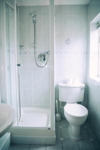 a white bathroom with a toilet and a shower at The Old Bakery in Kenilworth