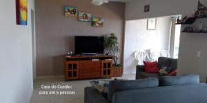 a living room with a couch and a flat screen tv at De frente para o Mar da Gamboa in Garopaba