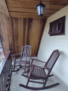 two rocking chairs on the porch of a cabin at Apartamento estilo chalé - Enxaimel in Bombinhas