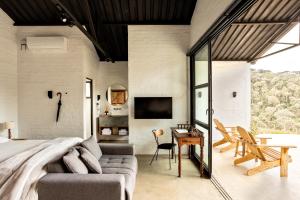 a bedroom with a bed and a desk and a tv at Mataka'a - Chalé Industrial na Mantiqueira in Gonçalves