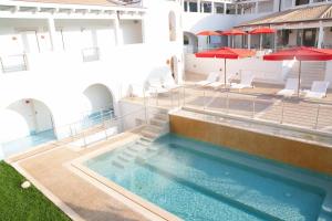 a swimming pool with chairs and umbrellas on a building at Ganimede Hotel in Sperlonga