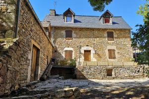 una antigua casa de piedra con una escalera delante de ella en Maison traditionnelle en Lozère, en Saint-Saturnin-de-Tartaronne