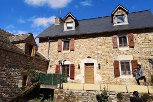 a man standing on the side of a stone house at Maison traditionnelle en Lozère in Saint-Saturnin-de-Tartaronne +4 photos