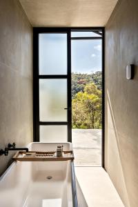 a bathroom with a window and a bath tub at Mataka'a - Chalé Industrial na Mantiqueira in Gonçalves