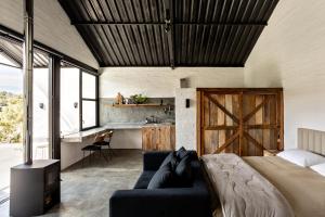 1 dormitorio con cama, sofá y escritorio en Mataka'a - Chalé Industrial na Mantiqueira, en Gonçalves